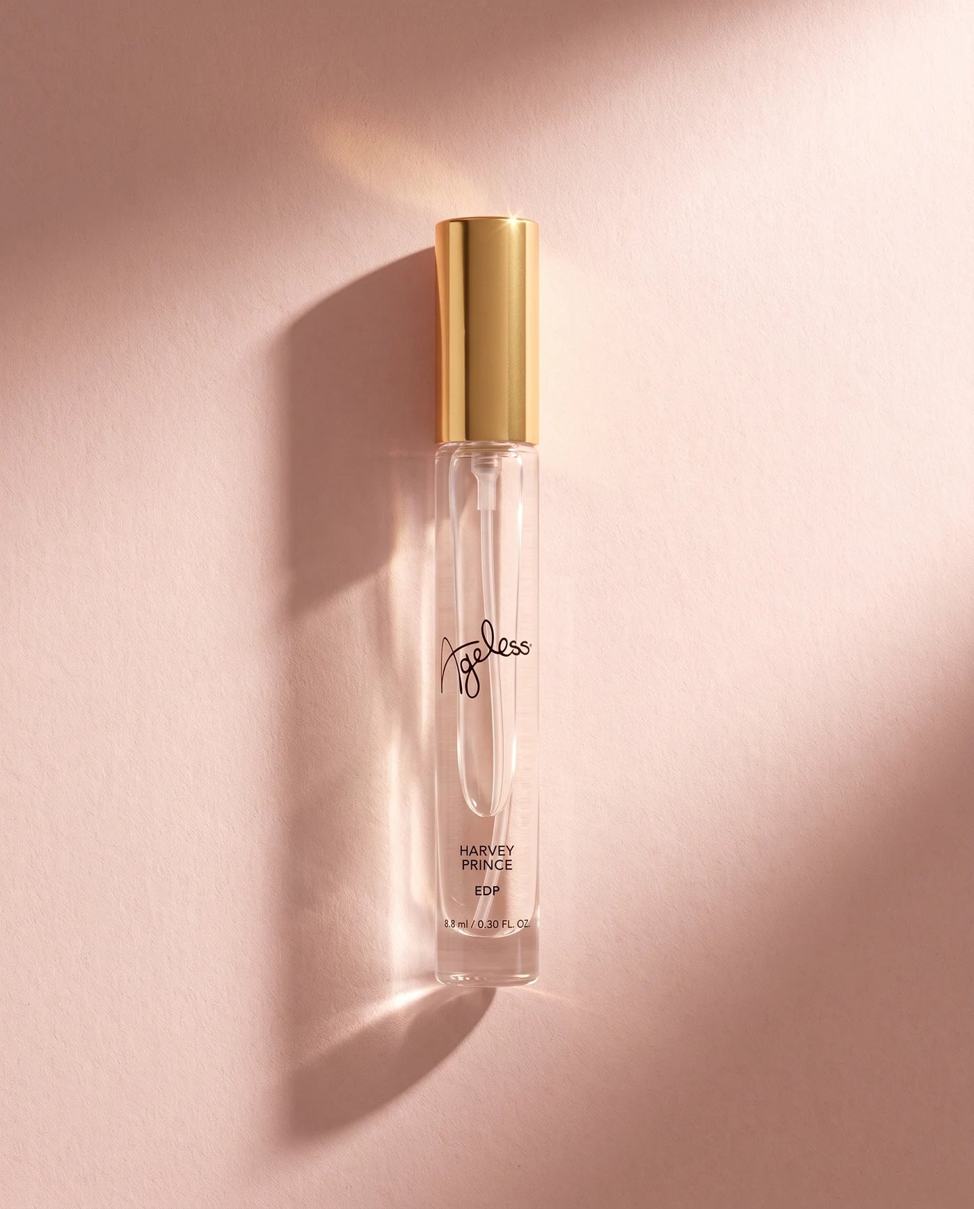 Harvey Prince Ageless travel fragrance with gold cap in warm sunlight